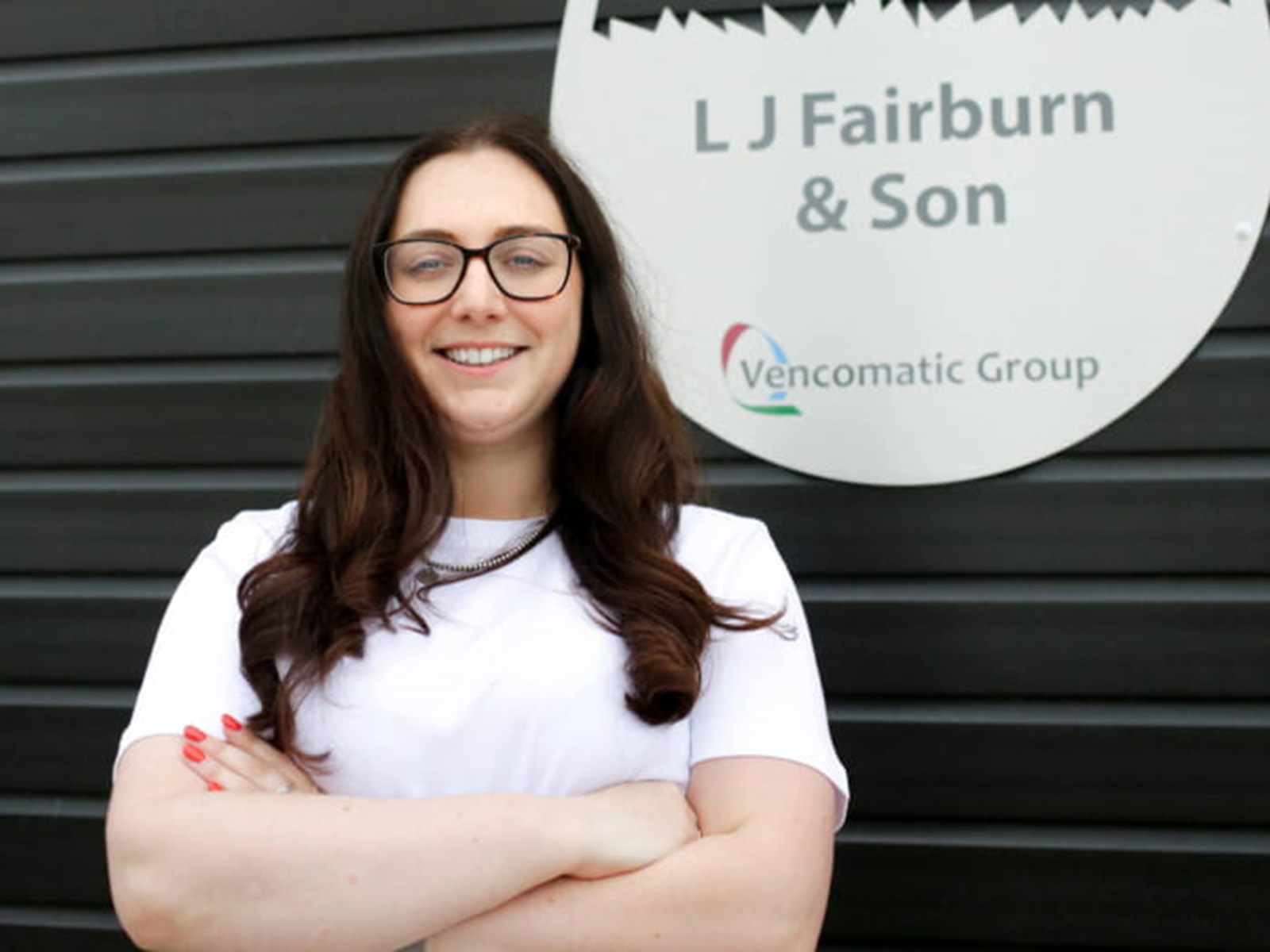 Louise Waters smiling in front of a Fairburn & Sons sign