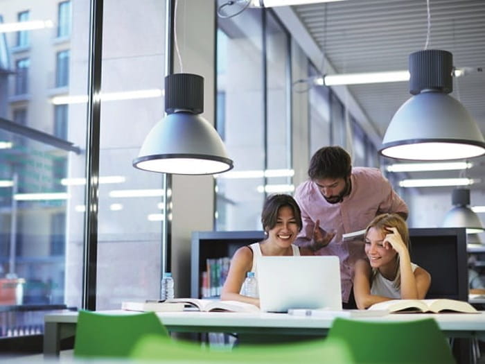 Three people huddled around desk