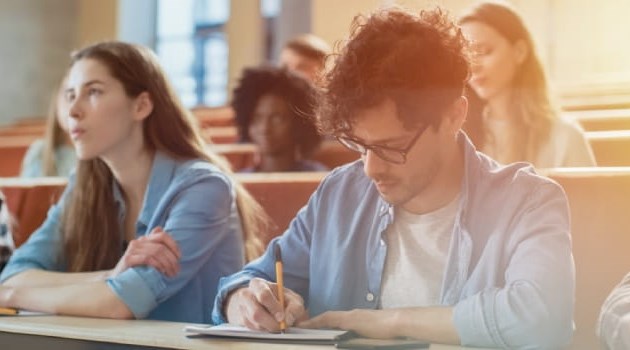 Male student taking notes during a lecture