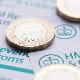 UK pound coins sitting on top of unspecified HMRC forms. 