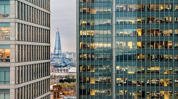 A building visible in the gap between two tall office buildings at dusk