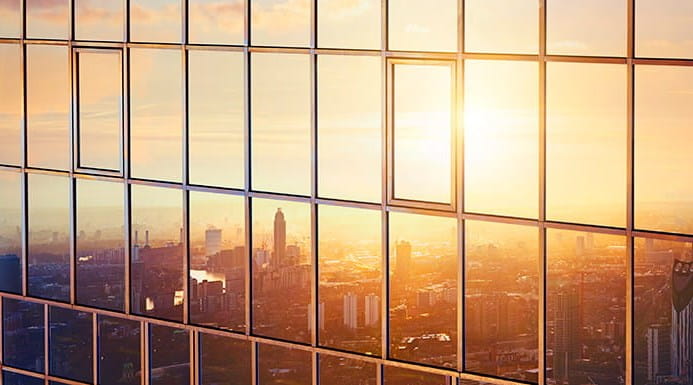 A cityscape at dusk seen in the reflection of an office building