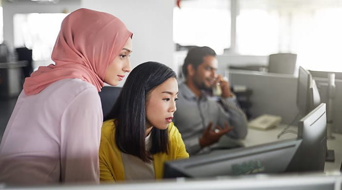 Two workers talking at a computer in an office