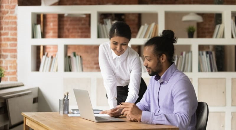 Young woman and man at a laptop in office