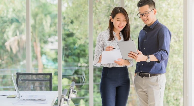 Young man and woman looking at documents in front of office window