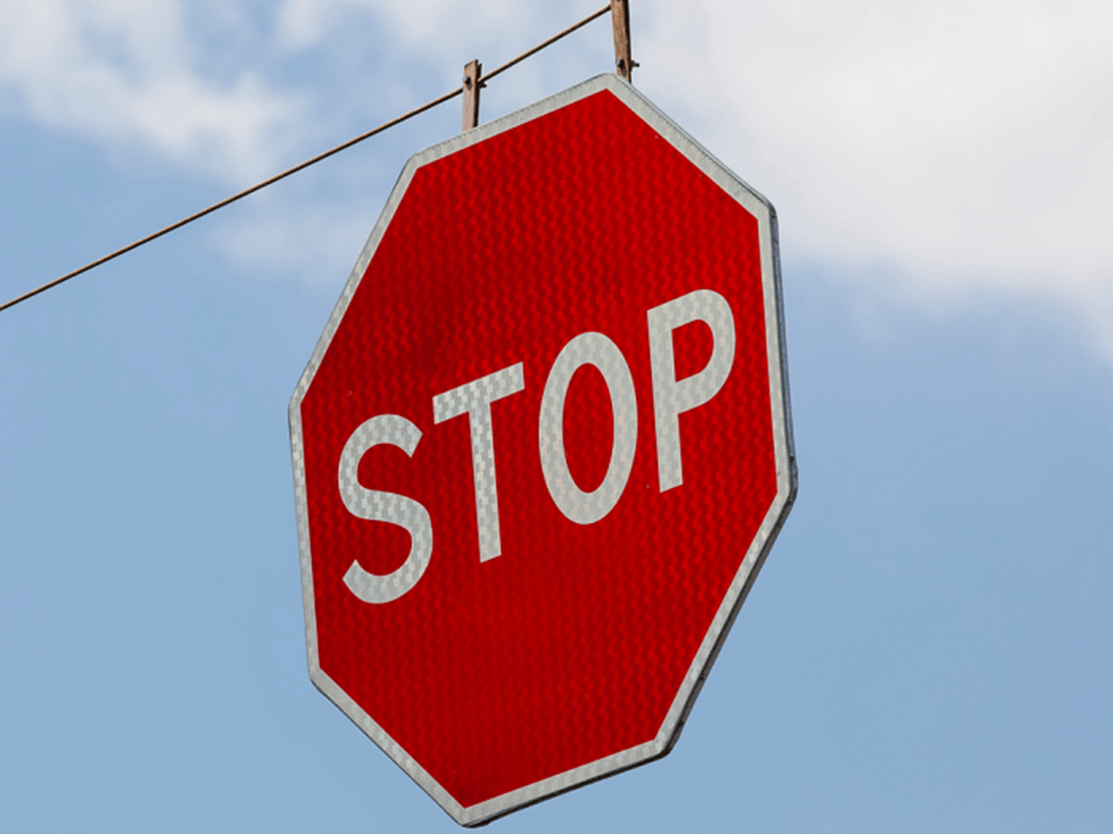 Red stop sign suspended from a cable