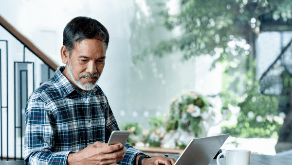 Man sat at his home office desk checking his phone